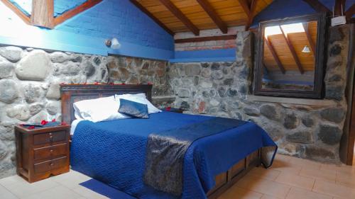 a bedroom with a bed and a stone wall at Destinos Exclusivos Patate in Patate