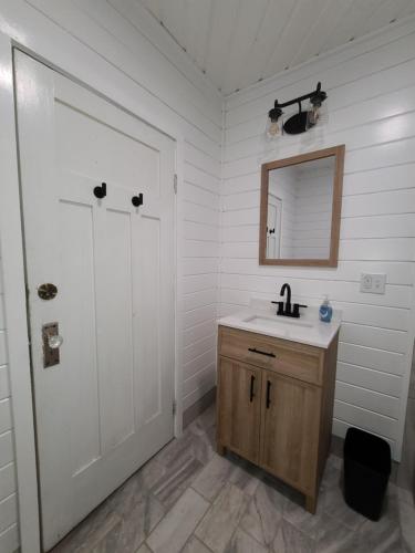 a bathroom with a sink and a mirror and a door at The Fairview Inn in Talkeetna