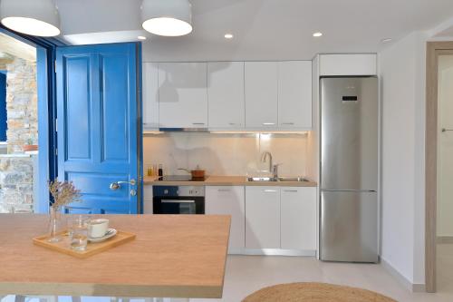 uma cozinha com armários brancos e uma porta azul em Villa & Studio Hydroussa by Andros Homes em Gavrion