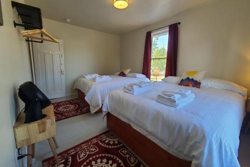 1 Schlafzimmer mit 2 Betten mit weißer Bettwäsche und einem Fenster in der Unterkunft The Fairview Inn in Talkeetna
