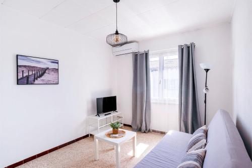 un salon blanc avec un canapé et une télévision dans l'établissement Bright apartment for a pleasant stay in Hyères, à Hyères
