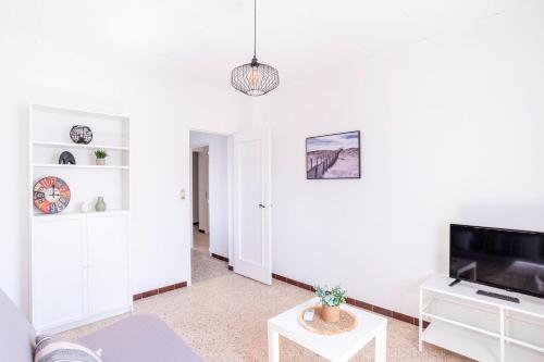 un salon blanc avec un canapé et une télévision dans l'établissement Bright apartment for a pleasant stay in Hyères, à Hyères