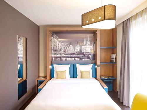 a bedroom with a large bed with a painting on the wall at Aparthotel Adagio Köln City in Cologne