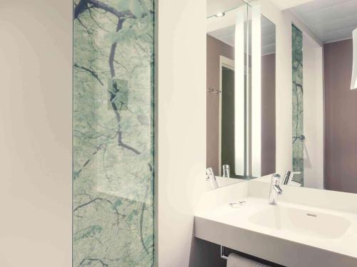 a bathroom with a shower with a sink and a mirror at Mercure Paris Ouest Saint Germain in Saint-Germain-en-Laye