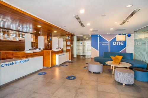 a lobby with a couch and a table and chairs at One Saltillo Aeropuerto in Saltillo