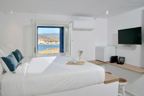 Un dormitorio blanco con una gran cama blanca y una ventana en Villa & Studio Hydroussa by Andros Homes, en Gavrion