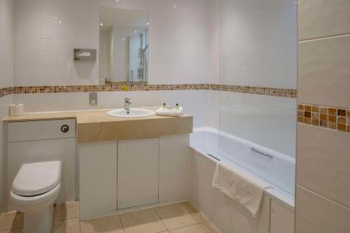 a bathroom with a toilet and a sink and a bath tub at Best Western Heath Court Hotel in Newmarket