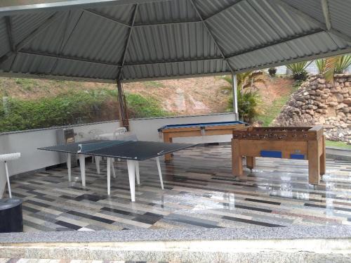 a ping pong table under a black umbrella at Pousada Recanto da Preguiça in Jarinu