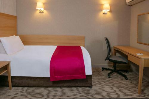 a room with a bed with a desk and a desk at Best Western Heath Court Hotel in Newmarket