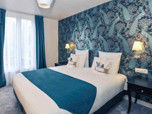 サン・クルーにあるメルキュール パリ サン クルー ヒッポドロームの大きなベッドと壁画が備わるホテルルームです。