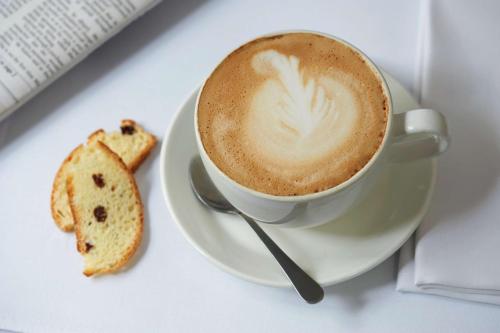 a cup of coffee and a cookie on a plate at StayEasy Pretoria in Pretoria