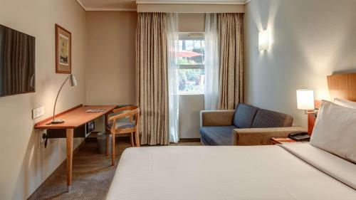a hotel room with a bed and a desk and a chair at StayEasy Pretoria in Pretoria