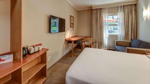 Pokój hotelowy z łóżkiem i biurkiem w obiekcie StayEasy Pretoria w mieście Pretoria