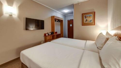 a hotel room with a white bed and a television at StayEasy Pretoria in Pretoria