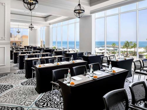 uma sala de jantar com mesas e cadeiras e o oceano em Fairmont Fujairah Beach Resort em Dibba
