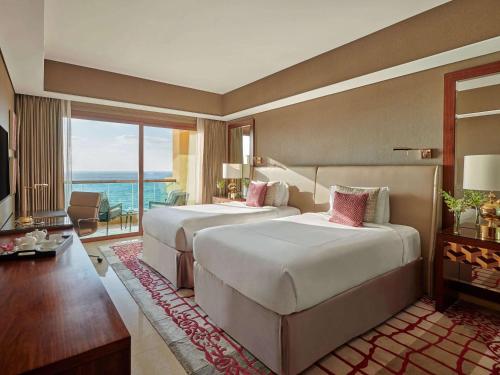 a hotel room with two beds and a balcony at Fairmont Ajman in Ajman 