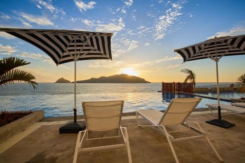 two chairs and umbrellas on a patio overlooking the ocean at Courtyard by Marriott Mazatlan Beach Resort in Mazatlán