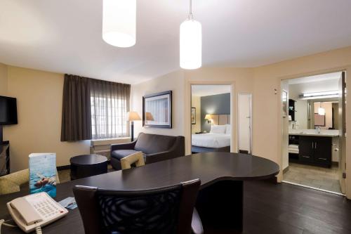 a living room with a table and a room with a bed at Sonesta Simply Suites St Louis Earth City in Earth City