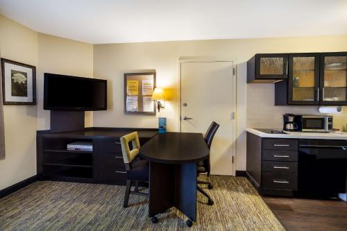 a room with a desk and a kitchen with a table and chairs at Sonesta Simply Suites St Louis Earth City in Earth City