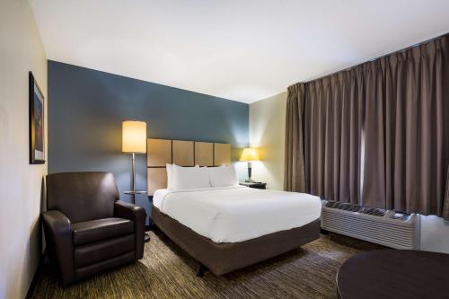 a hotel room with a bed and a chair at Sonesta Simply Suites St Louis Earth City in Earth City