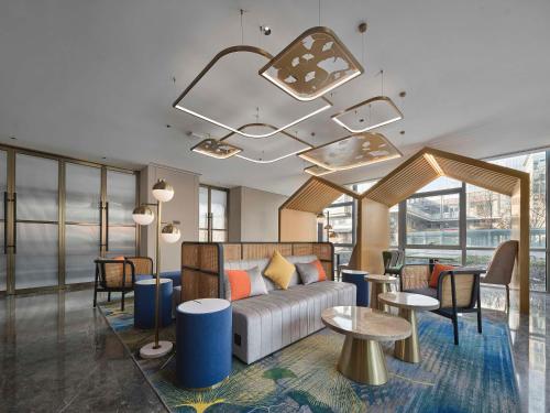 北京市にあるHilton Garden Inn Beijing Haidian Daoxiang Lakeのソファ、テーブル、窓が備わるホテルロビー