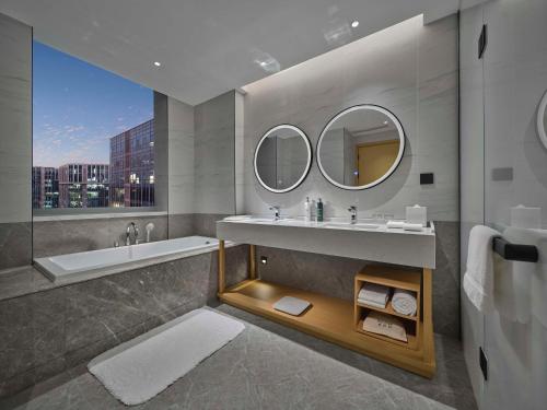 a bathroom with a sink and a tub and a mirror at Hilton Garden Inn Beijing Haidian Daoxiang Lake in Beijing