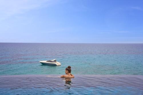 a woman in the water with a boat in the ocean at SEA ZANTE Luxury Beachfront Retreat in Tragaki