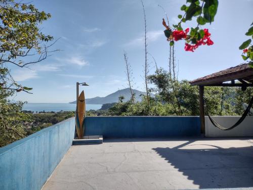 una tavola da surf appoggiata a un muro blu accanto a una recinzione di O melhor por do sol de Paúba! Casa Aconchegante. a São Sebastião