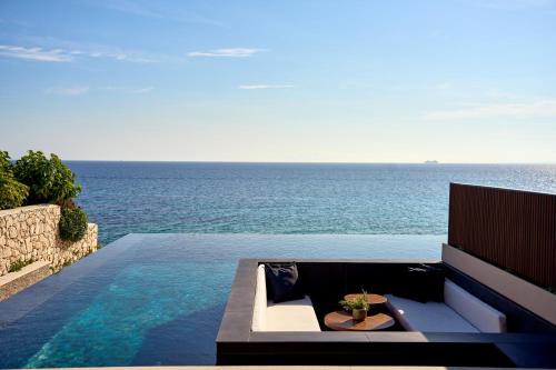 a swimming pool with a couch and the ocean at SEA ZANTE Luxury Beachfront Retreat in Tragaki