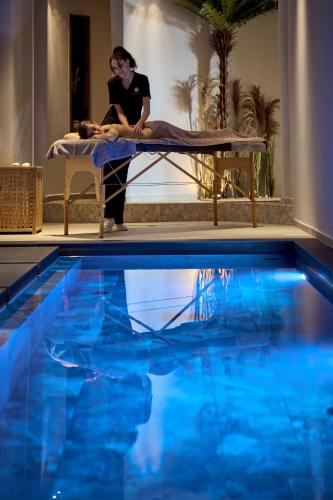a woman sitting on a bed next to a swimming pool at SEA ZANTE Luxury Beachfront Retreat in Tragaki