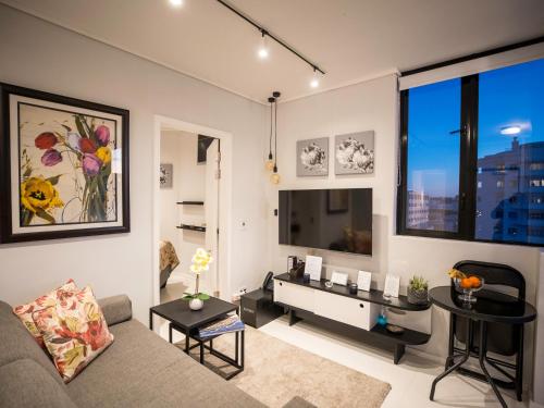 sala de estar con sofá y mesa en Flamingo Sea Point Sea View Luxury Best Position 1 Bedroom Apartment Queen Size Bed & Inverter For TV, en Ciudad del Cabo