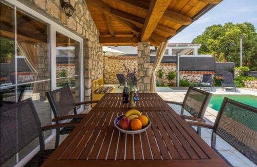 a bowl of fruit on a wooden table on a patio at Vintage Residence Dramalj, pool self-use in Dramalj