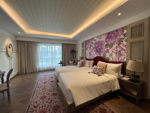 a bedroom with two beds and a floral wall at Nancy Tran Grand Strip Vung Tau Villa 6 in Vung Tau