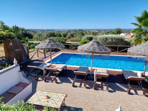 a swimming pool with chairs and umbrellas next to at Retiro da Janela in Boliqueime