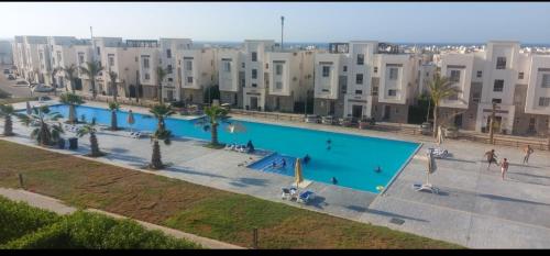 a large swimming pool in front of a large building at قريه امواج الساحل الشمالى in Sīdī ‘Abd ar Raḩmān