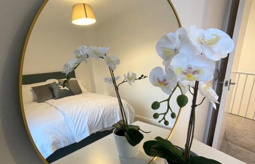 a mirror in a bedroom with a bed and white flowers at Contemporary-styled 3-Bed House in Buckinghamshire