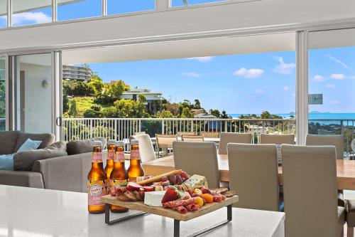 Airlie Beach的住宿－Coral View at Azure Sea，一张桌子,上面放有瓶装啤酒和一盘食物