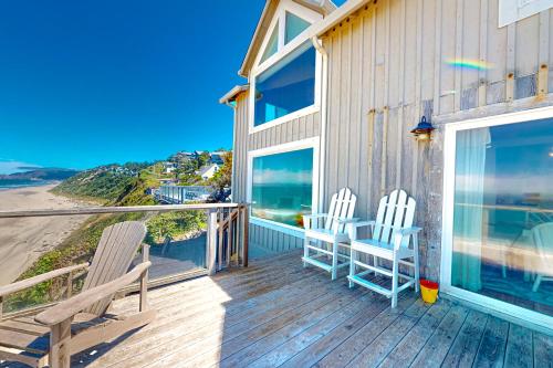 two chairs on a deck with a view of the ocean at Sea Cliff Cottage in Lincoln City