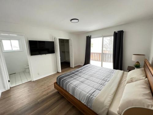 1 dormitorio con 1 cama grande y TV en Letitia Heights !E Spacious and Quiet Private Bedroom with Private Bathroom en Barrie