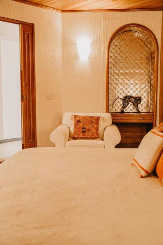 a bedroom with a bed and a chair and a mirror at Hotel Casa Pereyra in Oaxaca City