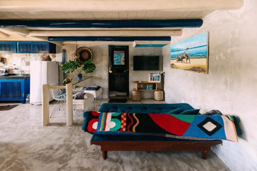 Casinha Azul Caraíva - casa completa na beira do Rio في كرايفا: غرفة معيشة مع أريكة ومطبخ