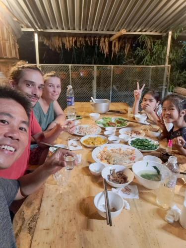 a group of people sitting at a table eating food at Homestay field - bungalow, Ha giang loop tour, motorbikes rental in Ha Giang