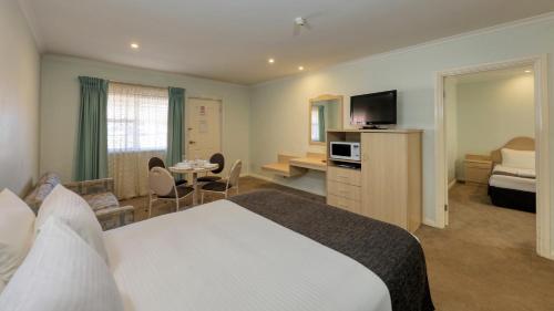 ein Hotelzimmer mit einem großen Bett und einem TV in der Unterkunft Charles Rasp Motor Inn & Cottages in Broken Hill