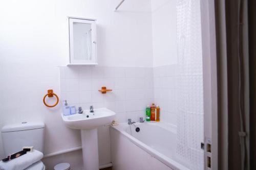 bagno bianco con lavandino, vasca e servizi igienici di The Green Lodge a Edmonton