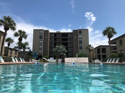 a large swimming pool with chairs and a building at Sea Club Condo #405 in Clearwater Beach