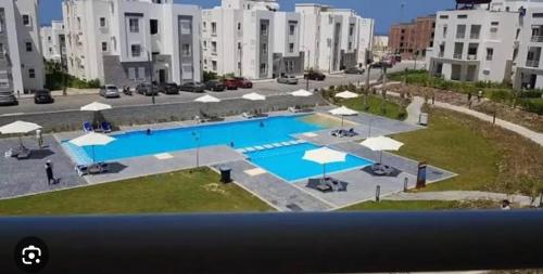 a large swimming pool with umbrellas in a city at قريه امواج الساحل الشمالى in Sīdī ‘Abd ar Raḩmān