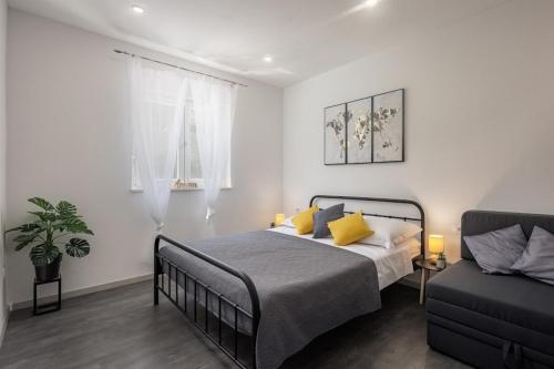 um quarto com uma cama com almofadas amarelas e um sofá em Family friendly apartments with a swimming pool Poljica, Trogir - 21592 em Marina