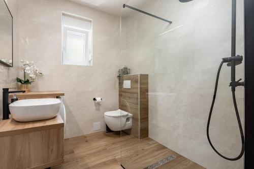 uma casa de banho com um chuveiro, um lavatório e um WC. em Family friendly apartments with a swimming pool Poljica, Trogir - 21592 em Marina