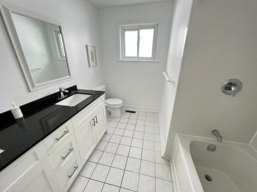 a white bathroom with a sink and a toilet at Letitia Heights !F Spacious and Stylish Private Bedroom with Shared Bathroom in Barrie