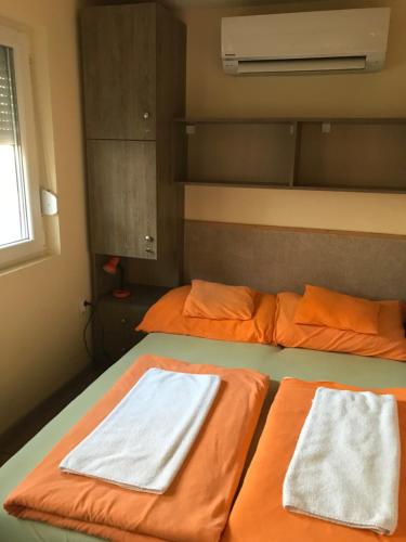 two beds in a room with orange and white towels at Tó- Party Panoráma Panzió & Wellness in Kiszombor